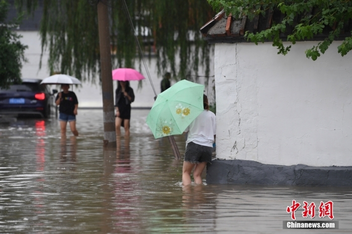 7月31日，市民行走在雨中的北京房山區瓦窯頭村。北京市氣象臺當日10時(shí)發(fā)布分區域暴雨紅色預警信號。北京市水文總站發(fā)布洪水紅色預警，預計當日12時(shí)至14時(shí)，房山區大石河流域將出現紅色預警標準洪水。<a target='_blank' href='/'><p  align=